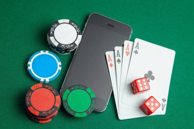 Cep telefonu casino online. Cep telefonu ve cips ve yeşil bir oyun masa üzerinde zar ile oyun kartları. Kumar bağımlılığı