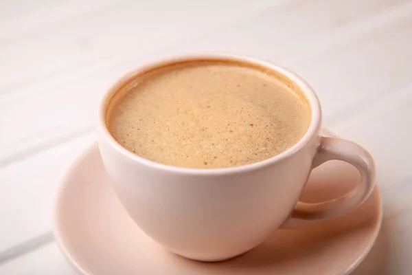 Чашка кофе с пеной на белом столе — стоковое фото