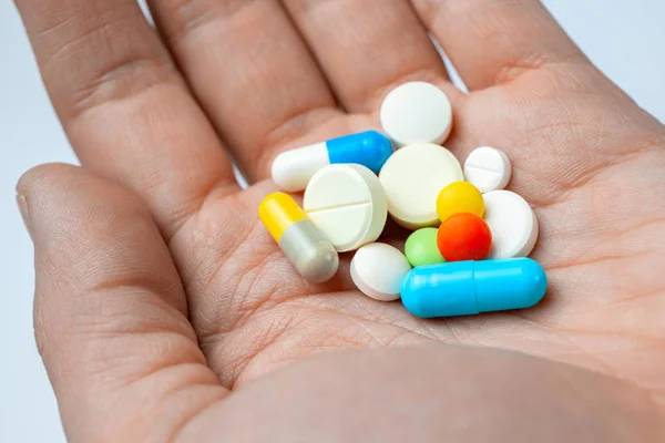 Muchas píldoras de color y cápsulas en la mano. primer plano — Foto de Stock
