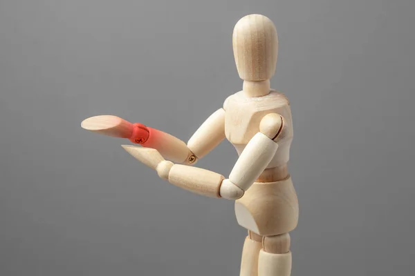 Dolor articular en el antebrazo. El hombre de madera sostiene su mano sobre su antebrazo en rojo — Foto de Stock
