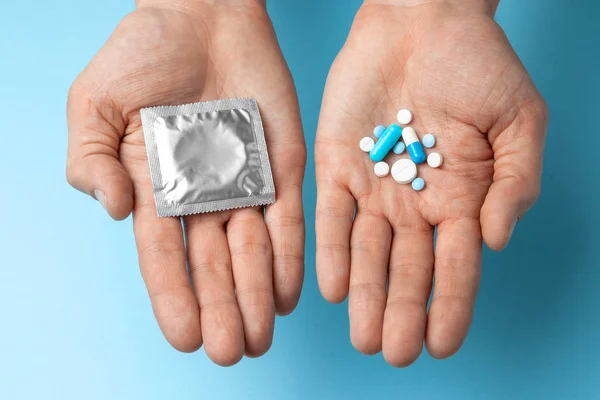 Concepto de elección de anticoncepción, píldora o condón. hombre en su mano son píldoras anticonceptivas en mordedor y en el condón de segunda mano — Foto de Stock