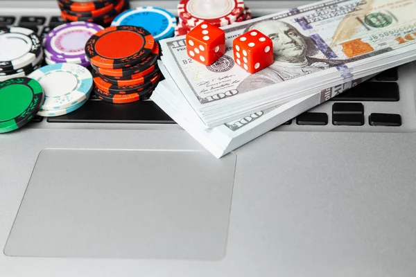 Lap-top online καζίνο. Πληκτρολόγιο lap-top και τα τσιπ με ζάρια και τα χρήματα σε μετρητά δολάρια στον πράσινο πίνακα τυχερού παιχνιδιού. Παιχνίδι εθισμού στα τυχερά παιχνίδια — Φωτογραφία Αρχείου