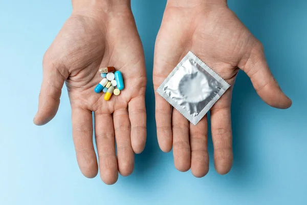 Concepto de elección de anticoncepción, píldora o condón. El hombre en su mano son píldoras anticonceptivas y en el condón de segunda mano — Foto de Stock