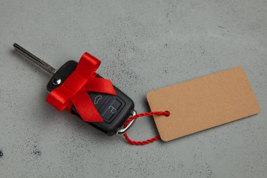 Araba anahtarları ile uzaktan kumanda alarm yay ve etiket etiket ile kırmızı kurdele ile hediye. Gri arka planı.