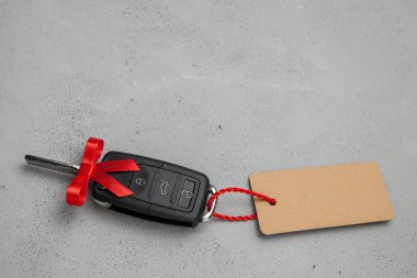Araba anahtarları ile uzaktan kumanda alarm yay ve etiket etiket ile kırmızı kurdele ile hediye. Gri arka planı