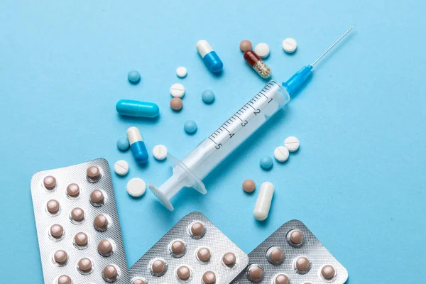 Pastillas anticonceptivas, una jeringa para inyección sobre fondo azul — Foto de Stock