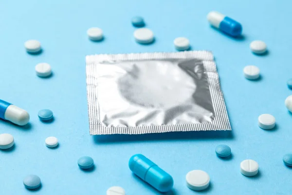 Birth control pills and condom on blue. Choosing method of contraception, birth control pills