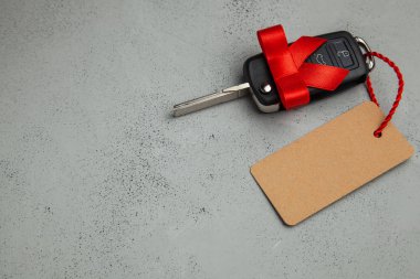 Araba anahtarları ile uzaktan kumanda alarm yay ve etiket etiket ile kırmızı kurdele ile hediye. Gri arka planı