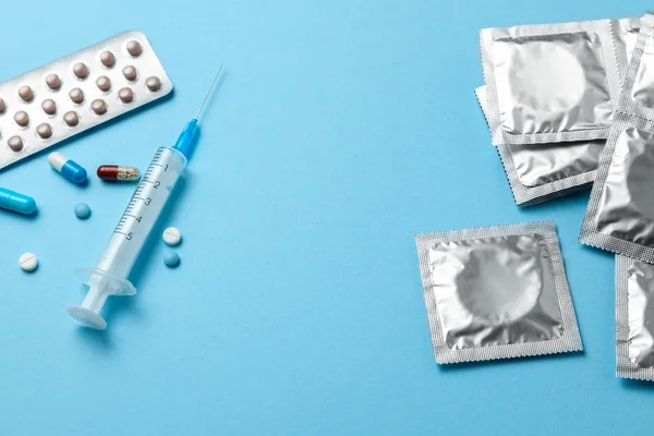 Pastillas anticonceptivas, una jeringa para inyección y condón en un envase en azul. método anticonceptivo — Foto de Stock