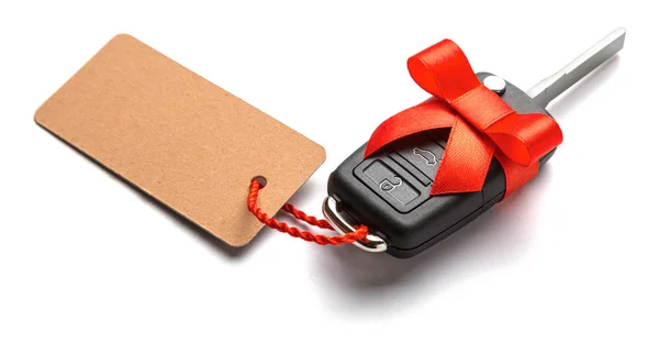 弓とラベルと赤リボン付きリモコン アラーム付きの車の鍵をプレゼントします。白で隔離 — ストック写真