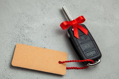 Araba anahtarları ile uzaktan kumanda alarm yay ve etiket etiket ile kırmızı kurdele ile hediye. Gri arka planı.