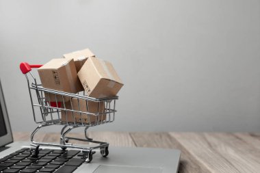 Çevrimiçi mağazadan teslim sipariş. Online alışveriş. Dizüstü bilgisayar ile masada alışveriş sepetindeki ürünler ile kutuları. Metin için yer kopyalayın.