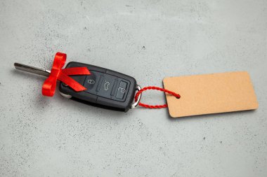 Araba anahtarları ile uzaktan kumanda alarm yay ve etiket etiket ile kırmızı kurdele ile hediye. Gri arka planı.