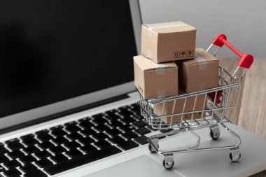 Çevrimiçi mağazadan teslim sipariş. Online alışveriş. Dizüstü bilgisayar ile masada alışveriş sepetindeki ürünler ile kutuları