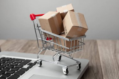 Çevrimiçi mağazadan teslim sipariş. Online alışveriş. Dizüstü bilgisayar ile masada alışveriş sepetindeki ürünler ile kutuları