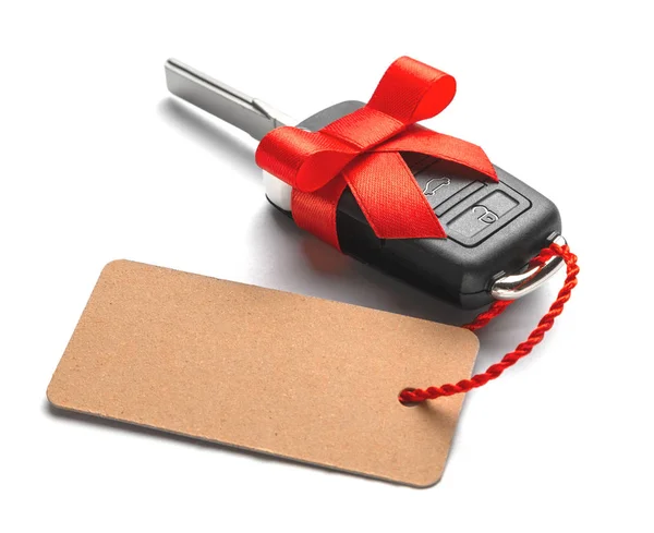 弓とラベルと赤リボン付きリモコン アラーム付きの車の鍵をプレゼントします。白い背景に分離. — ストック写真