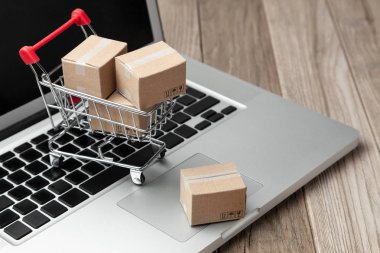 Çevrimiçi mağazadan teslim sipariş. Online alışveriş. Dizüstü bilgisayar ile masada alışveriş sepetindeki ürünler ile kutuları