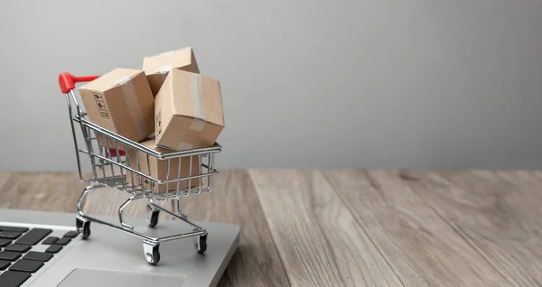 Entrega do pedido da loja online. Compras online. Caixas com mercadorias na cesta de compras na mesa com laptop. Espaço de cópia para texto . — Fotografia de Stock