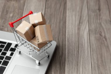 Çevrimiçi mağazadan teslim sipariş. Online alışveriş. Dizüstü bilgisayar ile masada alışveriş sepetindeki ürünler ile kutuları. Metin için yer kopyalayın.