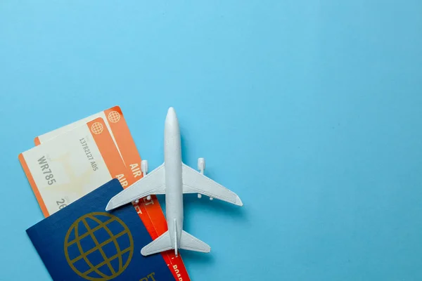 Billetes para avión y pasaporte con modelo de avión de pasajeros sobre fondo azul. Copiar espacio para texto . — Foto de Stock