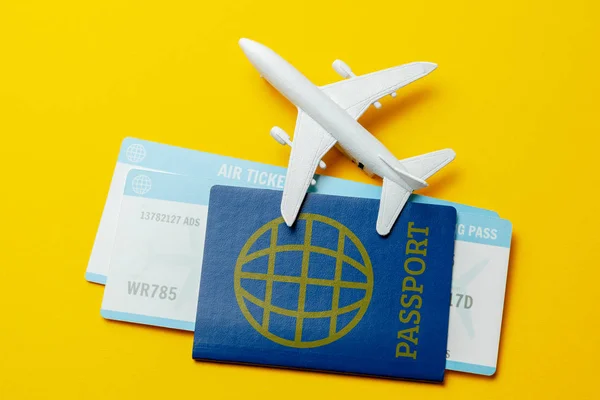 Billetes para avión y pasaporte con modelo de avión de pasajeros sobre fondo amarillo — Foto de Stock