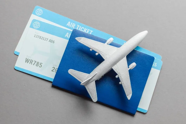 Billetes para avión y pasaporte con modelo de avión de pasajeros sobre fondo gris — Foto de Stock