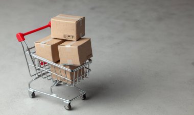 Online mağaza mal satın alma. Gri arka plan üzerinde alışveriş sepetindeki karton kutular.