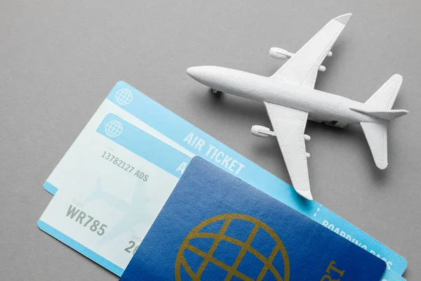 Tickets for plane and passport with model of passenger plane on gray background — Stock Photo, Image