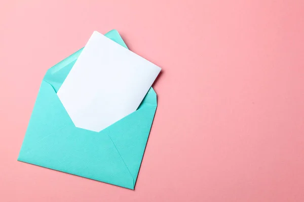 Grüner Umschlag und leerer Brief auf rosa Hintergrund. Attrappe. — Stockfoto