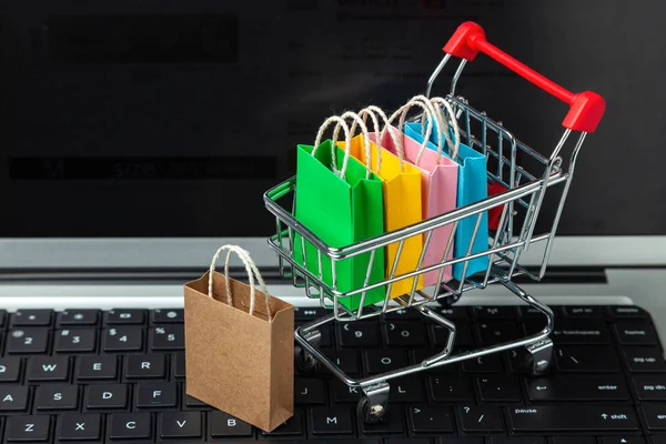 Membeli barang dan pakaian di toko online. Shopping bags in shopping cart on laptop keyboard — Stok Foto