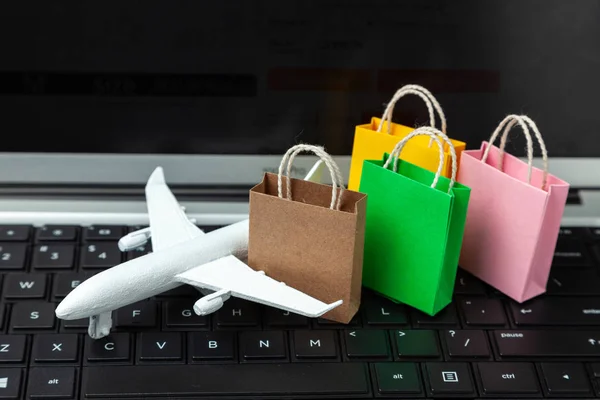 Delivery of goods and clothing from the online store with another country. Shopping bags and cruise plane on laptop keyboard