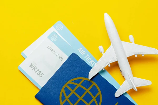 Billetes para avión y pasaporte con modelo de avión de pasajeros sobre fondo amarillo — Foto de Stock