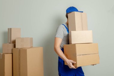 Hareketli bir gün. Online mağazada alışveriş teslim mal. Yükleyici veya kurye gri duvara karton kutular taşıma