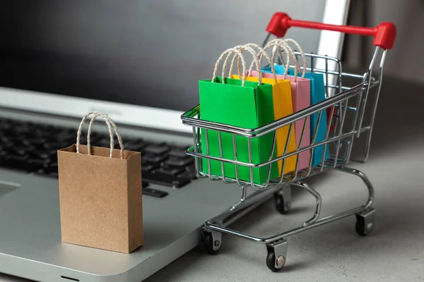 Membeli barang dan pakaian di toko online. Shopping bags in shopping cart on laptop keyboard — Stok Foto