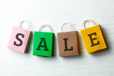 Satılık Beyaz arka plan üzerinde yazıt ile renkli alışveriş torbaları.