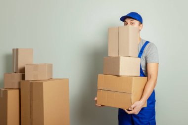 Hareketli bir gün. Online mağazada alışveriş teslim mal. Yükleyici veya kurye gri duvara karton kutular taşıma