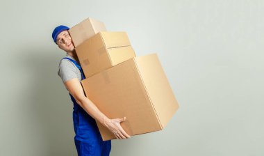 Hareketli bir gün. Online mağazada alışveriş teslim mal. Yükleyici veya kurye gri duvar karşı ağır karton kutular taşır