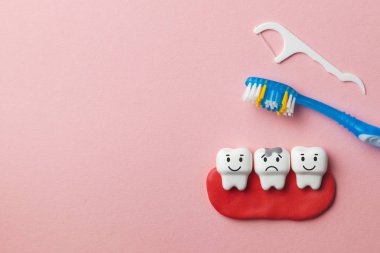 Sağlıklı beyaz dişler gülümsüyor ve diş çürüğü ile pembe bir arka plan ve diş fırçası ve diş ipi üzücü. Metin için yer kopyalayın.