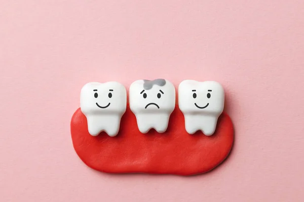 Zdravé bílé zuby se usmívají a zub s kazem je smutné na růžovém pozadí. — Stock fotografie