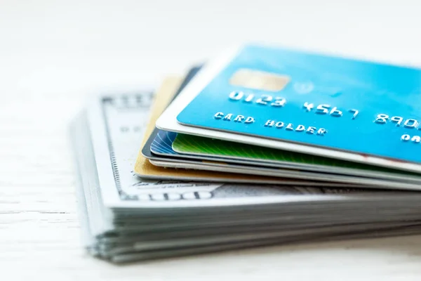 Carta di credito e pila di dollari in contanti su sfondo bianco . — Foto Stock