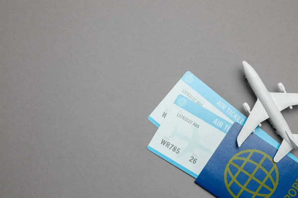 Billetes para avión y pasaporte con modelo de avión de pasajeros sobre fondo gris. Copiar espacio para texto — Foto de Stock