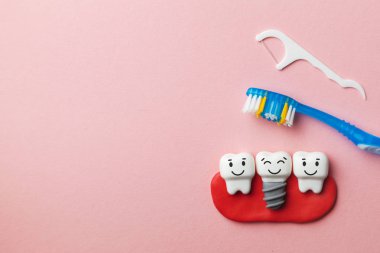 Sağlıklı beyaz dişler ve implantlar ile diş fırçası ve diş ipi pembe arka plan üzerinde gülümsüyorsun. Metin için yer kopyalayın.