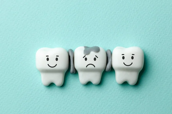 Healthy white teeth are smiling and tooth with caries is sad on green mint background. — Stock Photo, Image