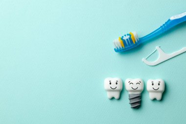 Sağlıklı beyaz dişler ve implantlar diş fırçası ve diş ipi nane yeşil zemin üzerine gülümsüyorsun. Metin için yer kopyalayın.