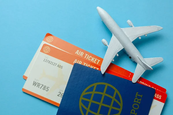 Billetes para avión y pasaporte con modelo de avión de pasajeros sobre fondo azul — Foto de Stock