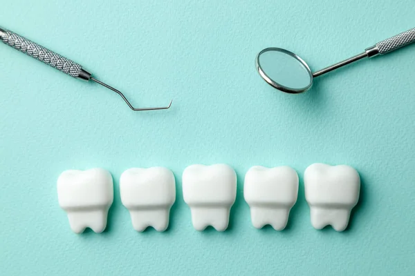 Здорові білі зуби на зеленому м'ятному фоні та інструменти стоматолога дзеркало, гачок . — стокове фото