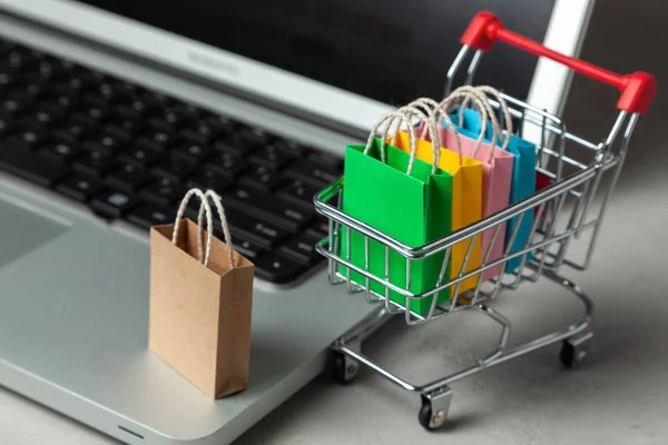 Membeli barang dan pakaian di toko online. Shopping bags in shopping cart on laptop keyboard — Stok Foto