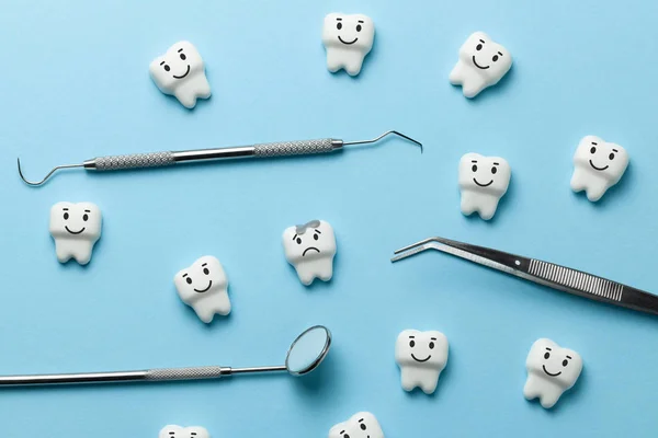 Dent blanche avec caries sur fond bleu et miroir outils dentiste, crochet . — Photo