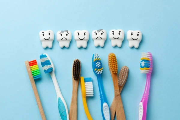 Dentes brancos saudáveis estão sorrindo e dente com cárie é triste no fundo azul e escova de dentes . — Fotografia de Stock