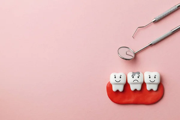 Dentes brancos saudáveis estão sorrindo e dente com cárie é triste em fundo rosa e ferramentas de dentista espelho, gancho. Espaço de cópia para texto . — Fotografia de Stock